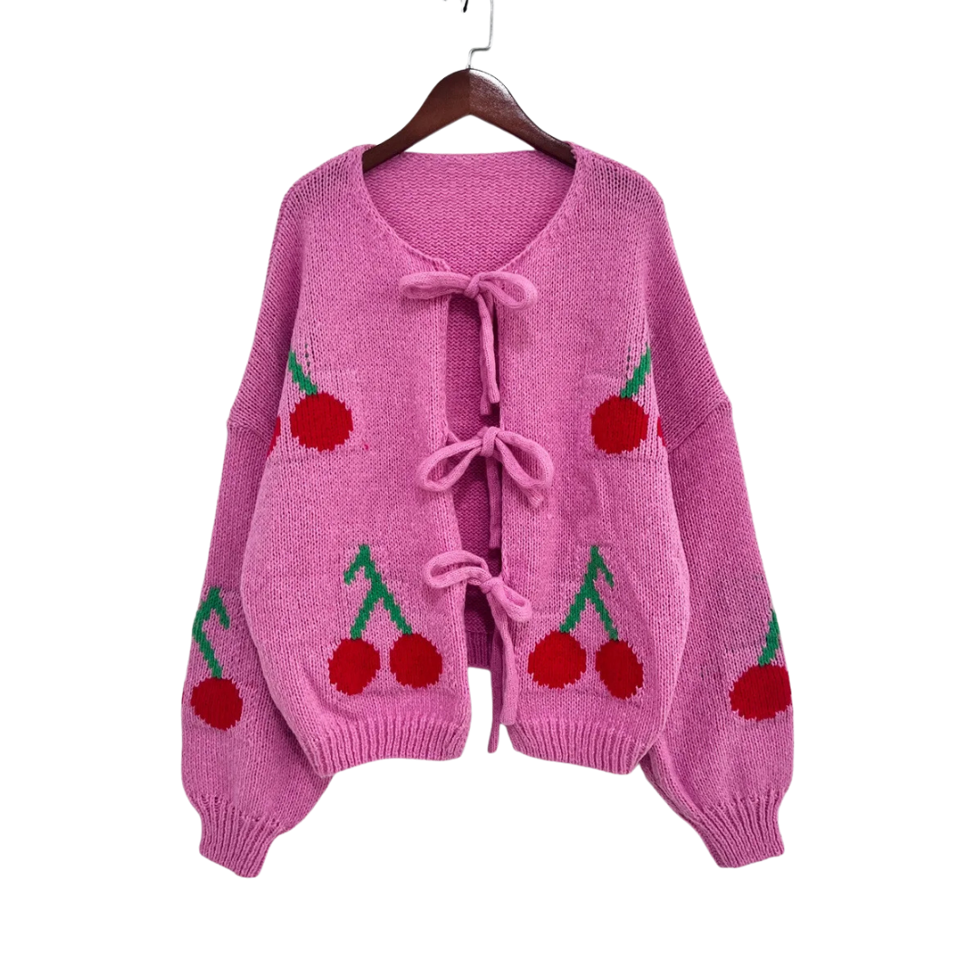 Pink knitted cardigan with cherry designs on a white background