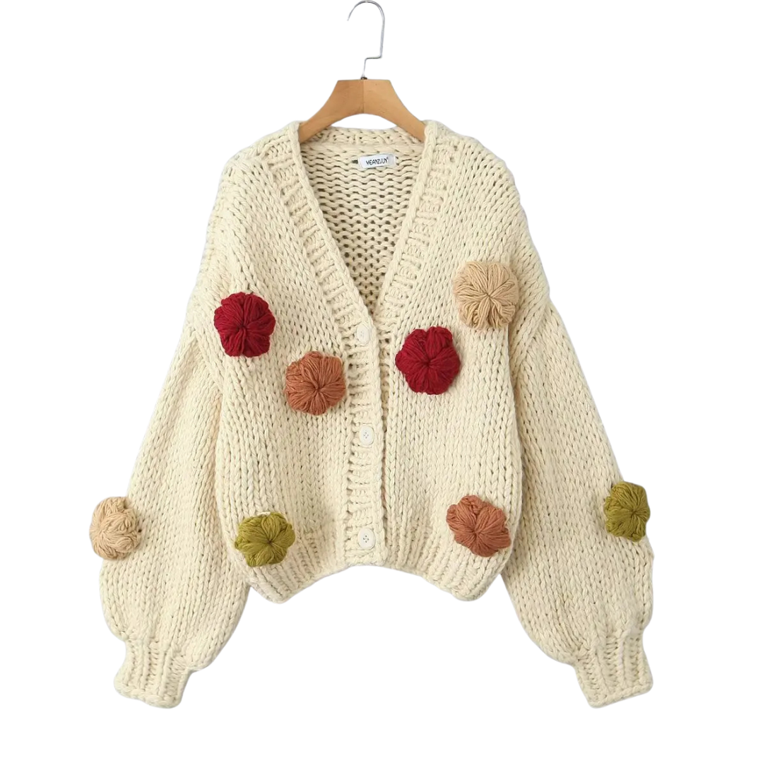 Knitted cardigan with colorful pom-poms on a white background